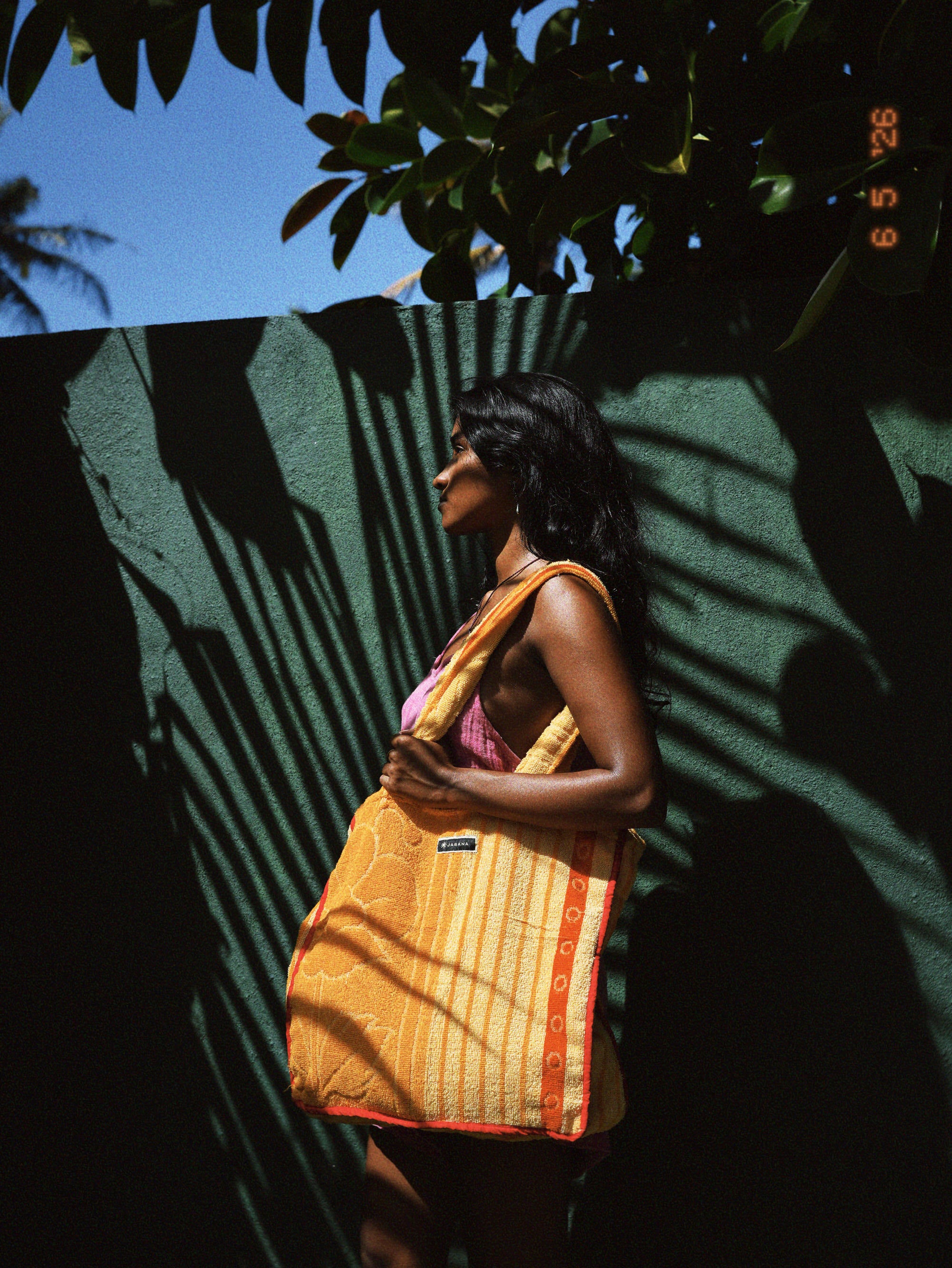 Woman carrying a yellow tote bag made from an upcycled Sri Lankan towel, shown worn in a natural lifestyle setting