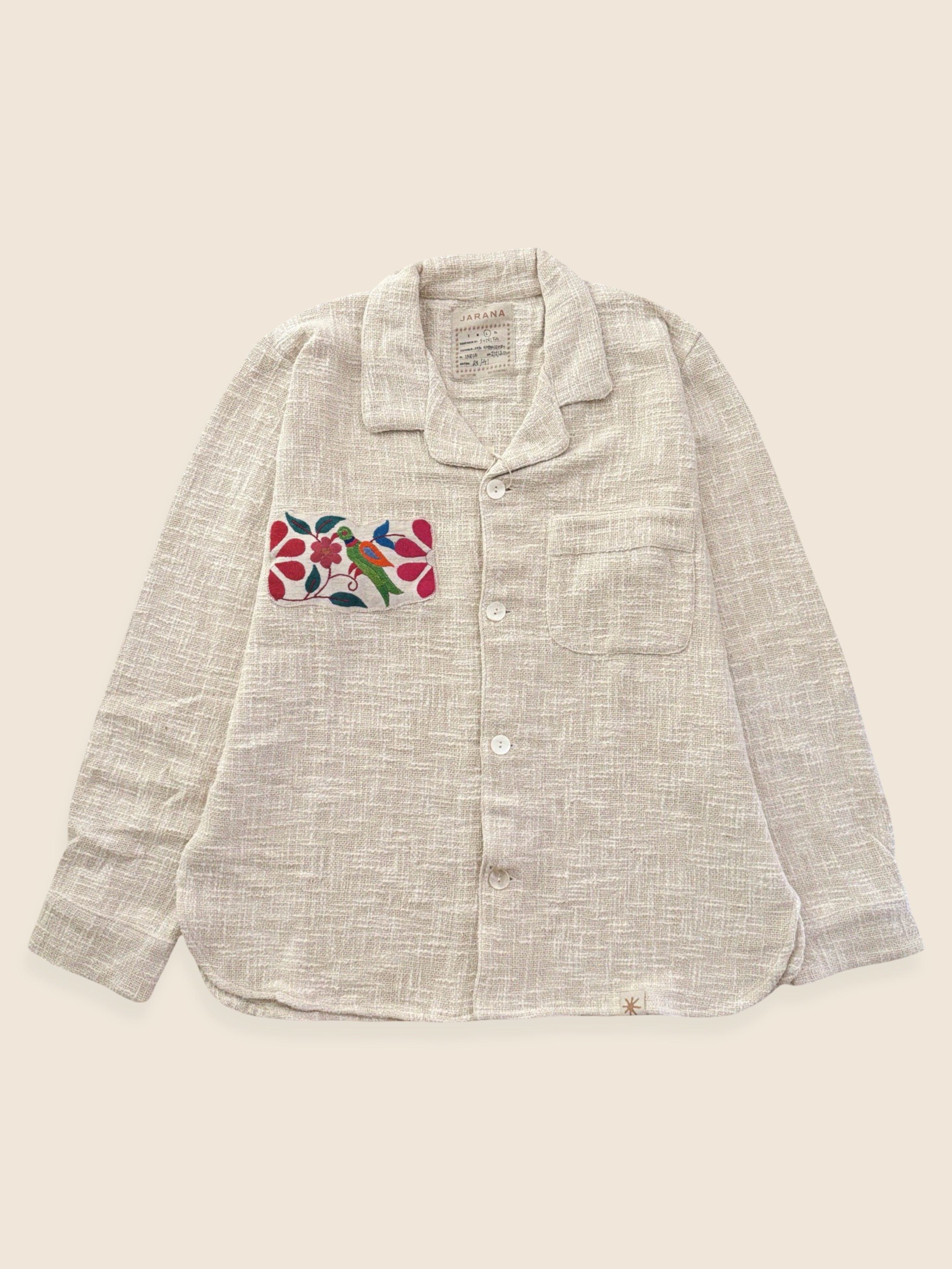 Light gray shirt with floral embroidery on a beige background