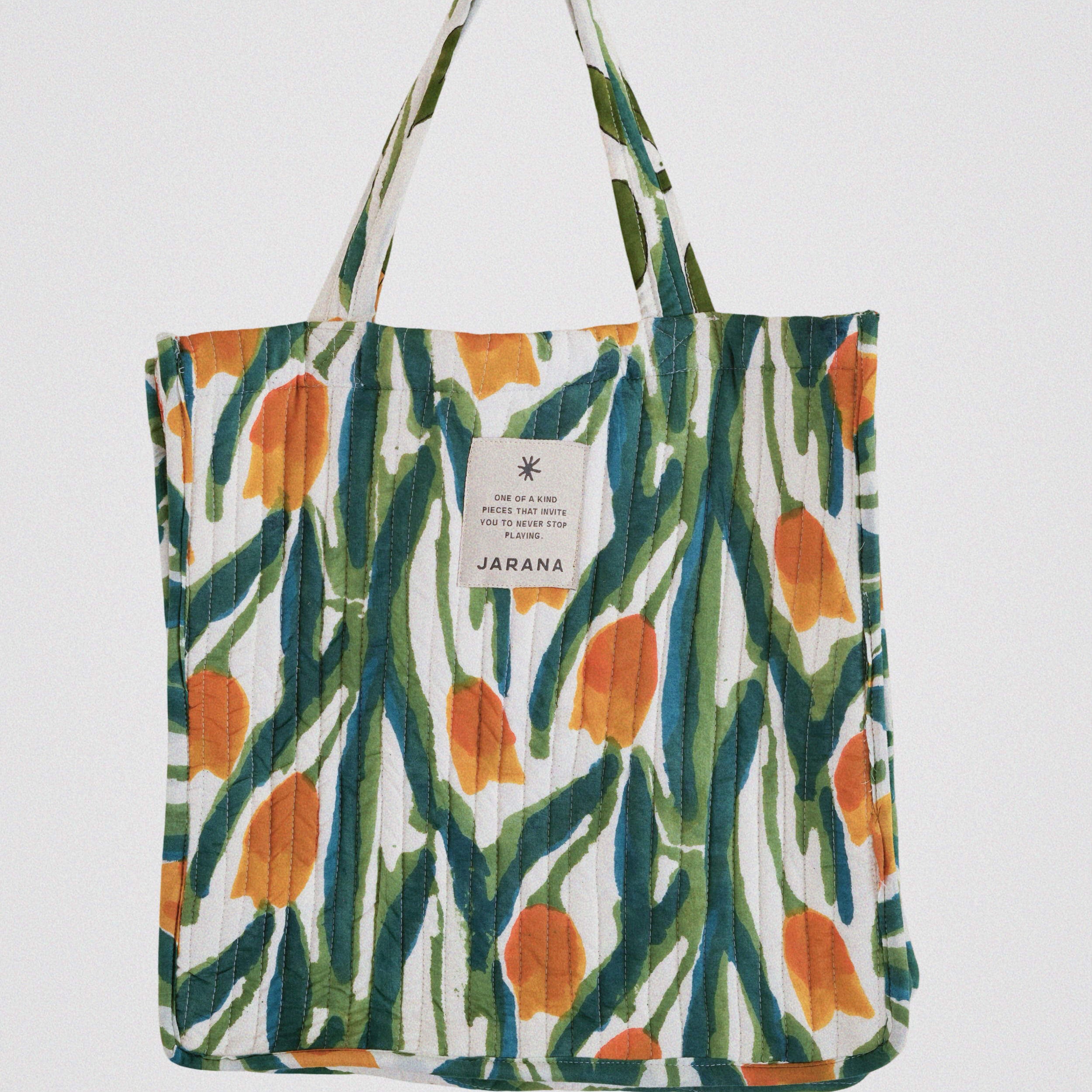 Vibrant quilted tote bag with hand-printed abstract floral design in green, orange, and blue, crafted from natural cotton.