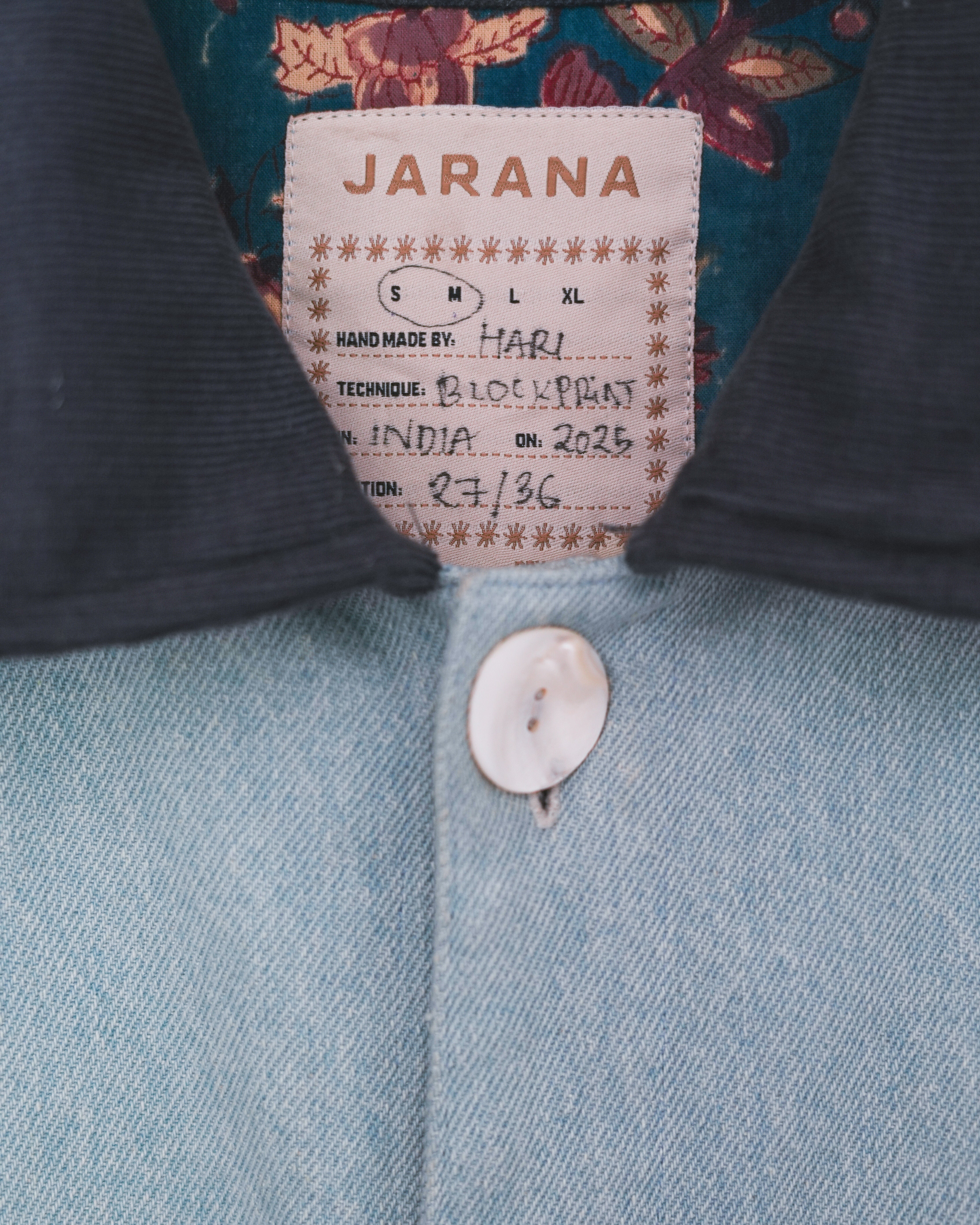 Close-up of Jarana label on denim jacket with visible blockprint lining and corduroy collar