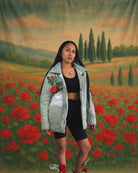 Model wearing handmade green-striped quilted jacket by Jarana, styled with red roses and set against a vintage rose field backdrop