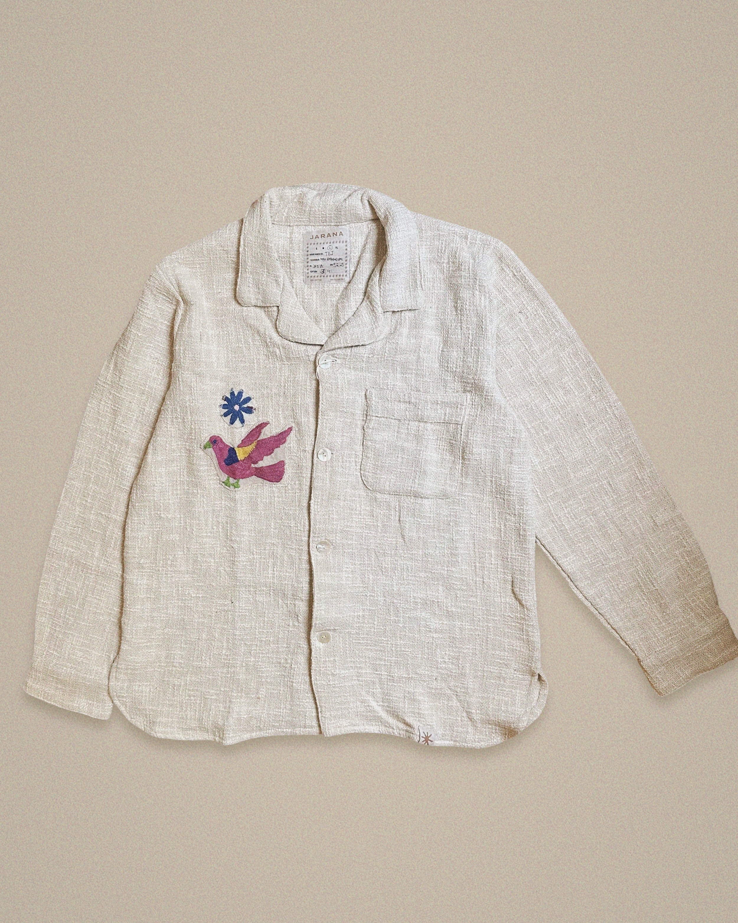 Handmade cotton shirt with purple and green bird embroidery flying beneath a blue starburst β Jarana limited edition