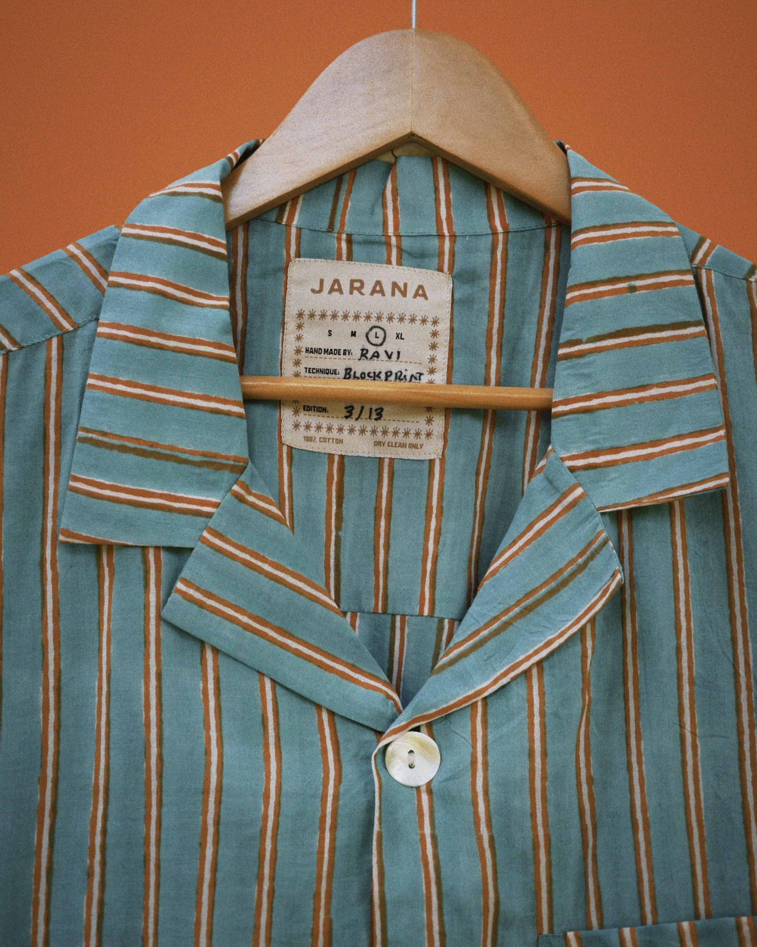 Collar and placket of teal cotton shirt with clay-brown vertical stripes and natural shell button.