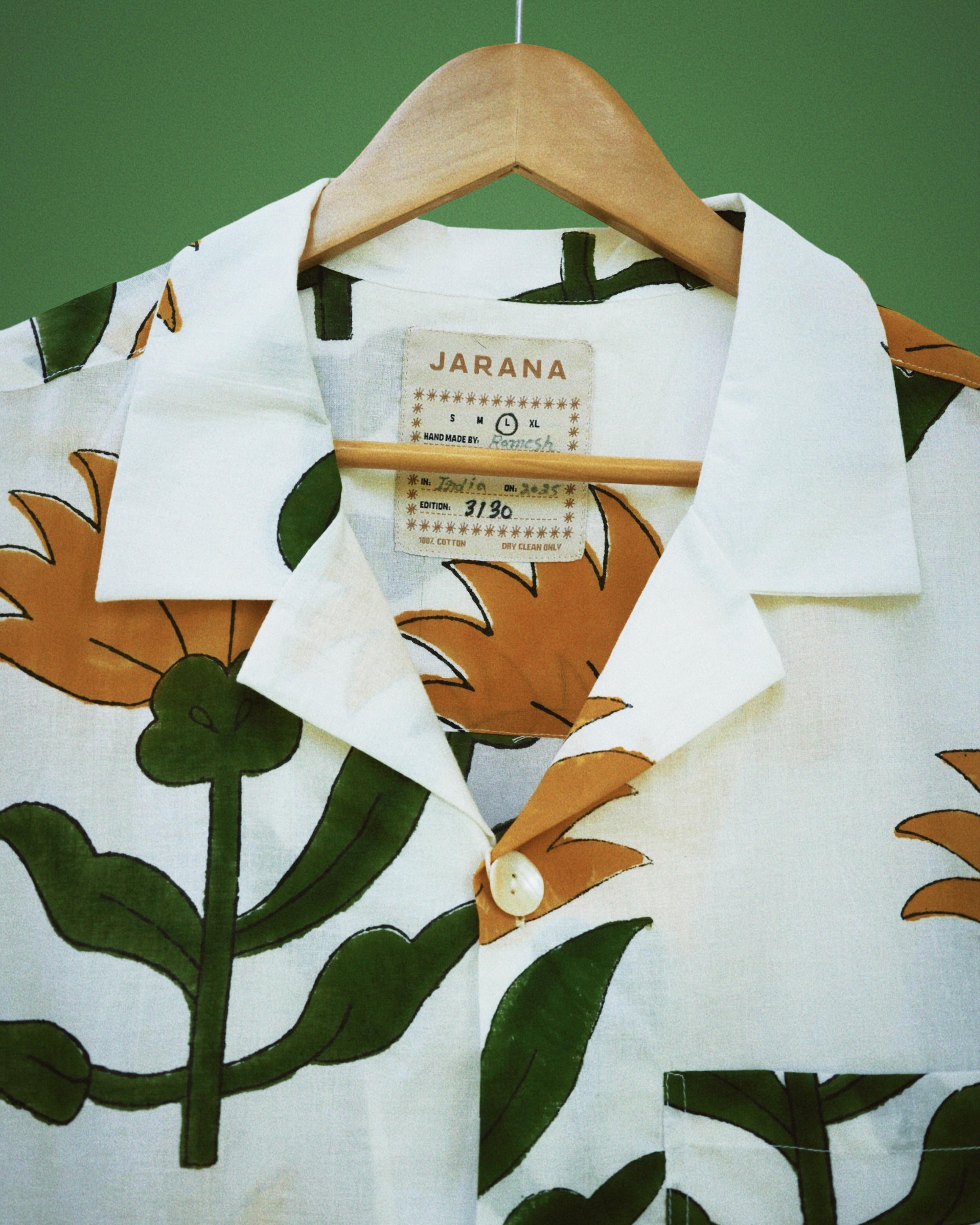 White cotton shirt featuring oversized sunflower and leafy green block print around the collar.