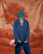 Model in blue block-printed Kantha shirt holding flowers, showcasing traditional floral embroidery