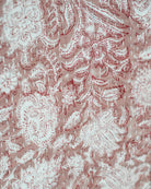 Close-up of hand-stitched Kantha embroidery in red and white floral pattern on soft cotton fabric