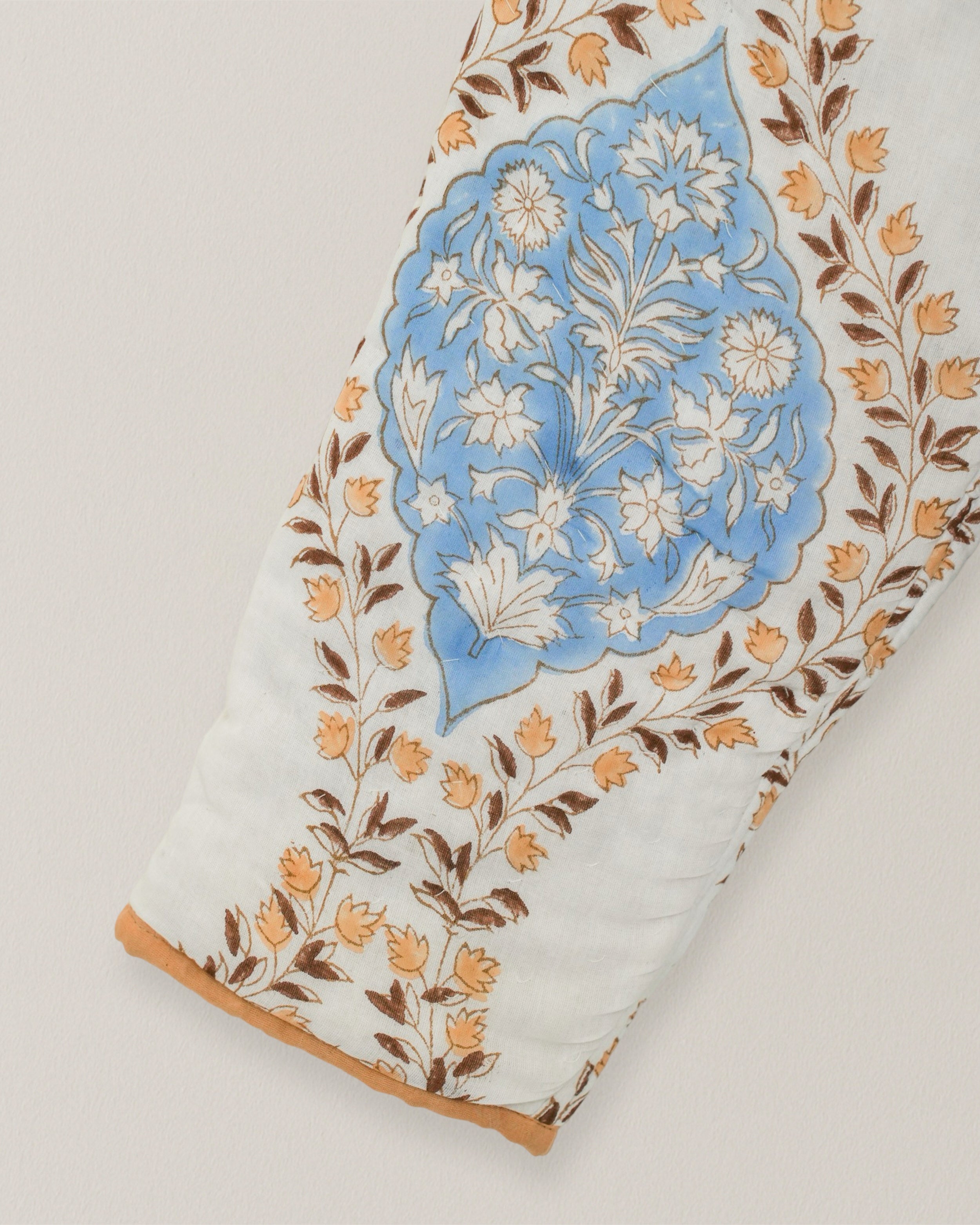 Close-up of quilted sleeve featuring blue floral blockprint motif with tan and brown leaf accents