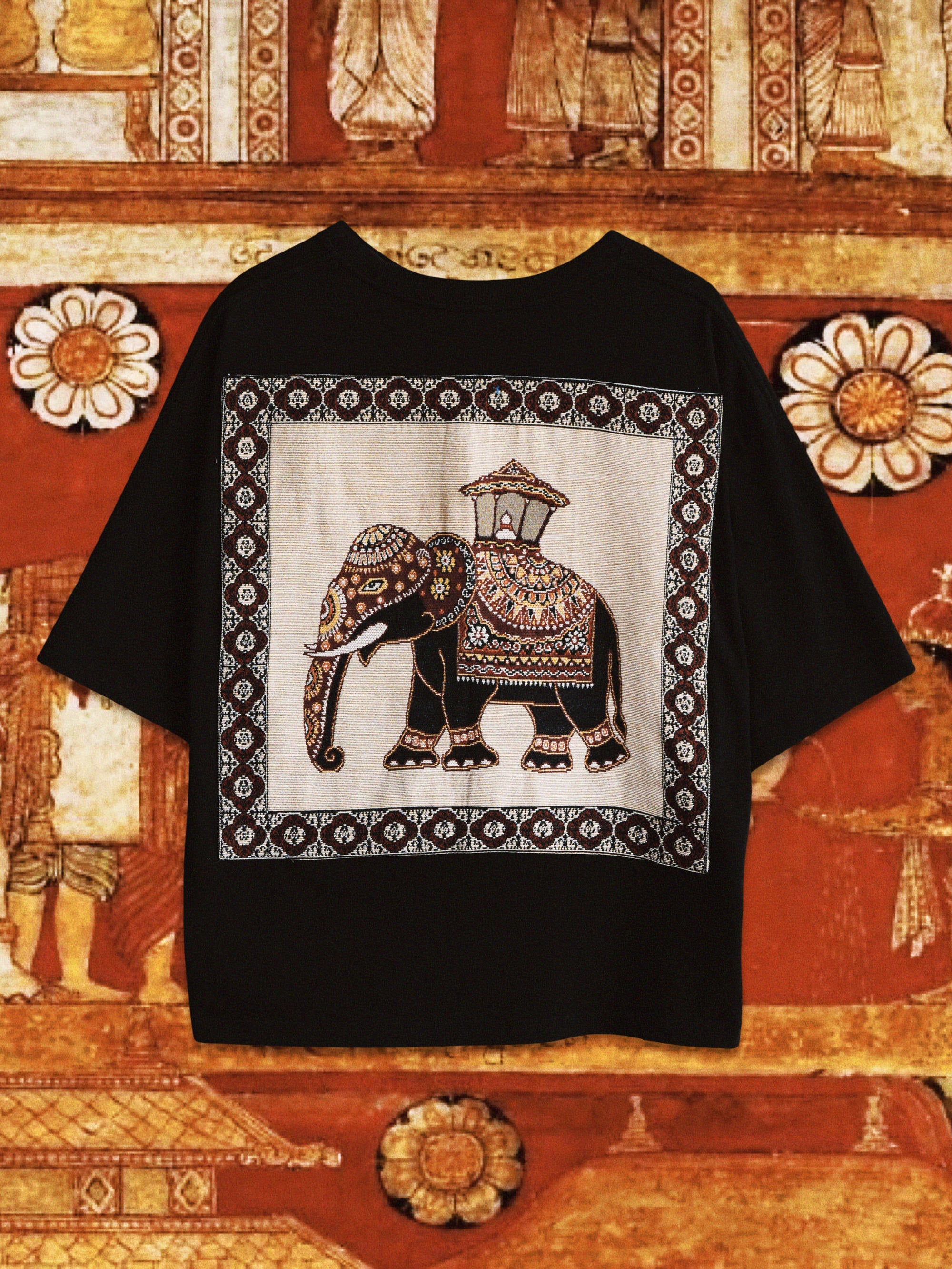 Black t-shirt with an elephant design tapestry from Kandy on a decorative background