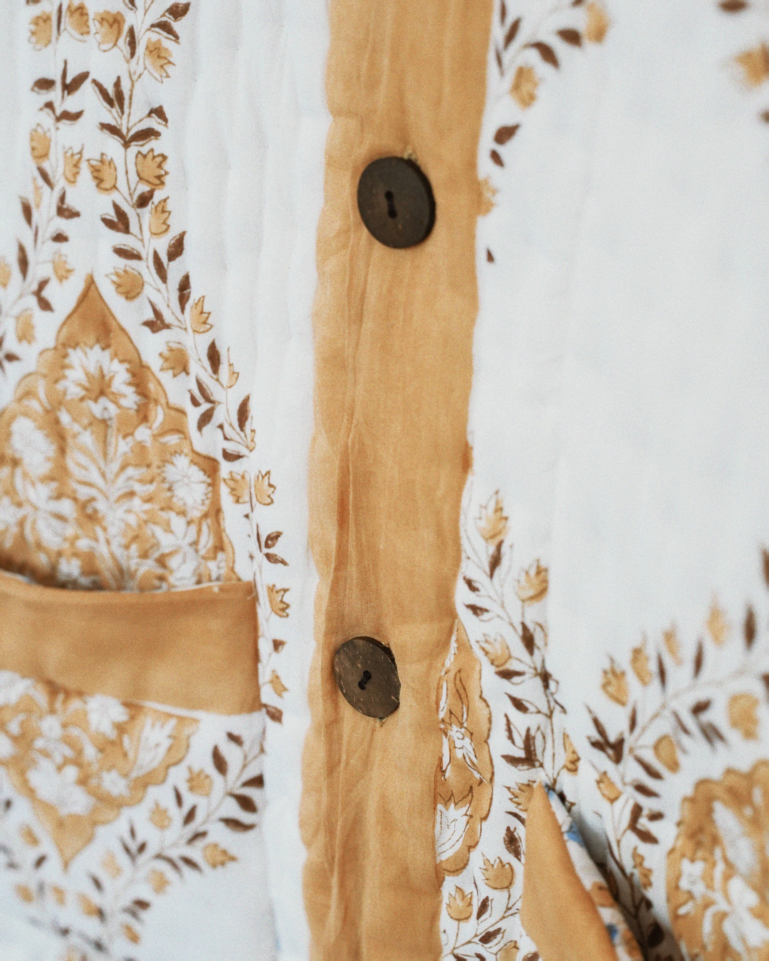 Close-up of a shirt with floral patterns and wooden buttons.