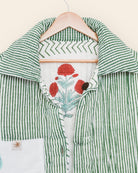 Green and white striped shirt with floral design on a hanger