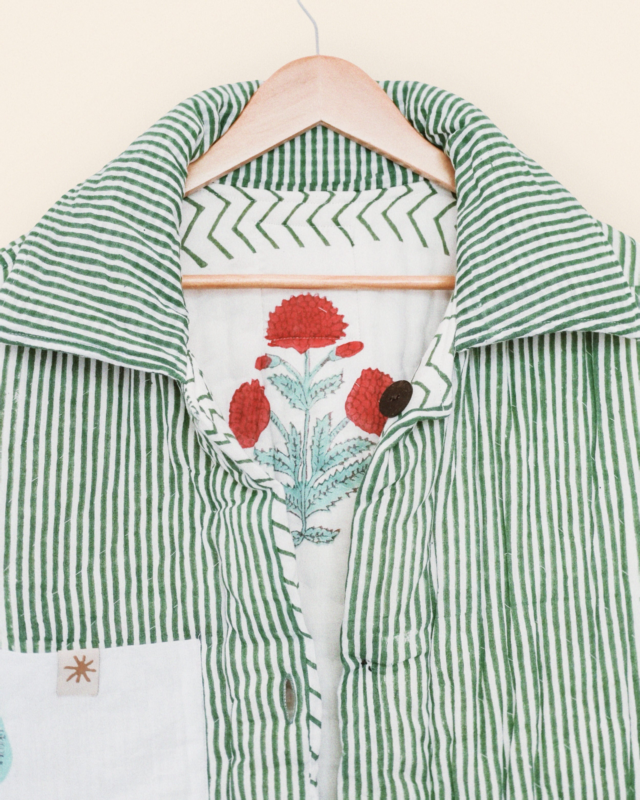 Green and white striped shirt with floral design on a hanger