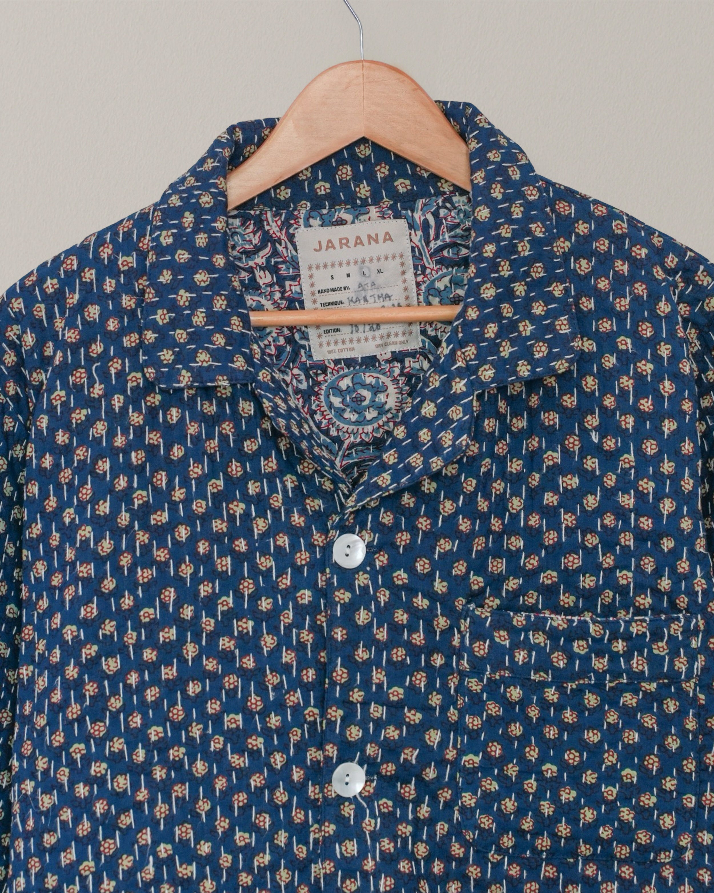 Close-up of collar and label of blue Jarana shirt, featuring detailed Kantha hand embroidery