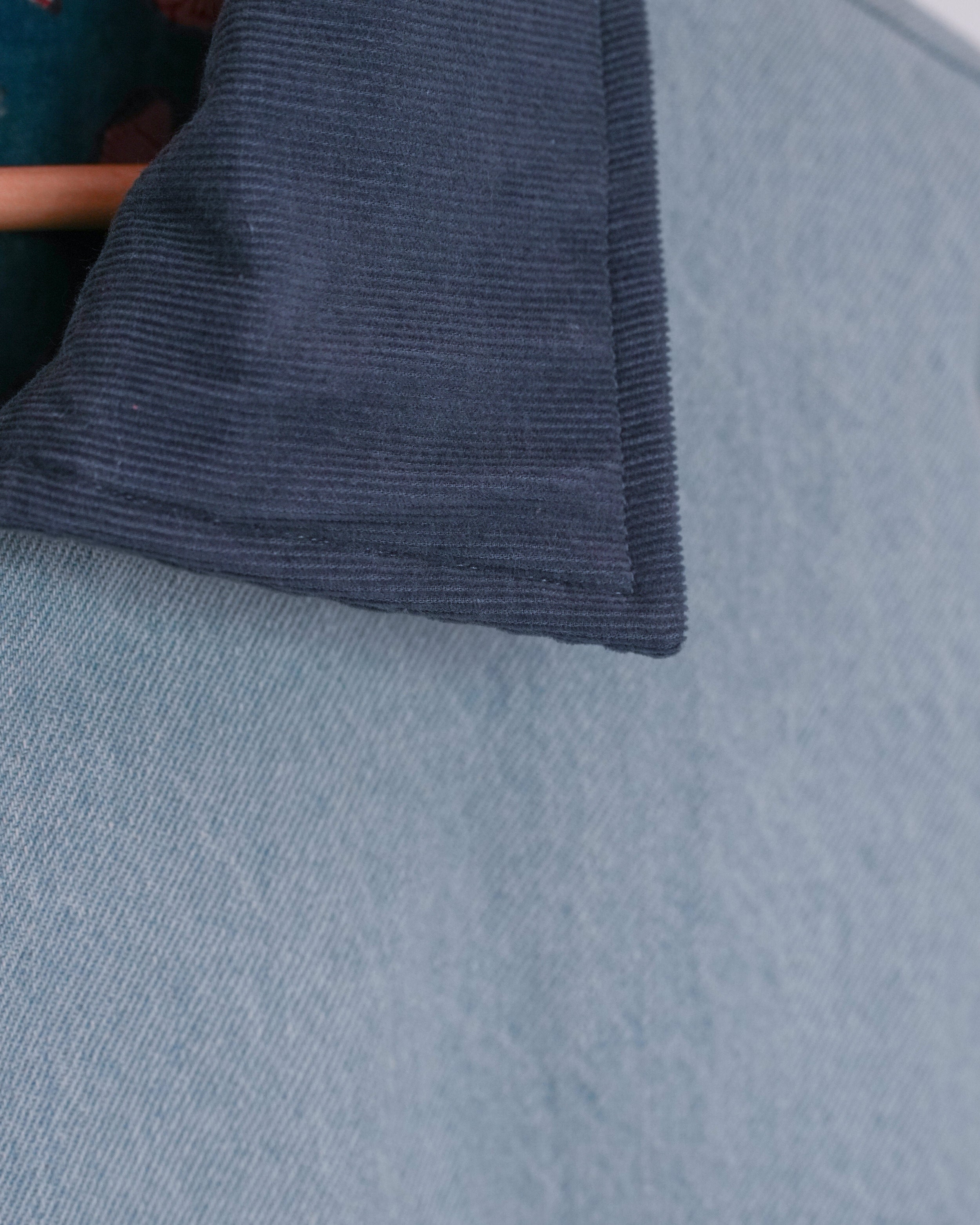 Detail of dark corduroy collar on light blue jean-inspired jacket