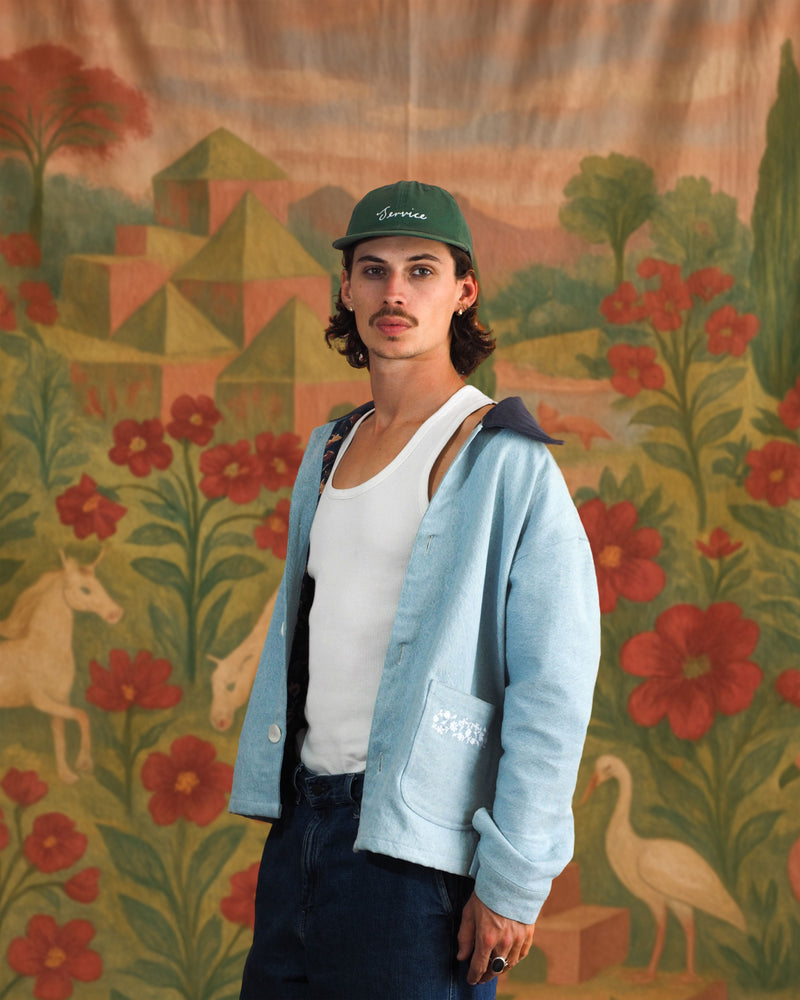 Model wearing light blue denim-style Jarana jacket with white floral embroidery and contrast collar