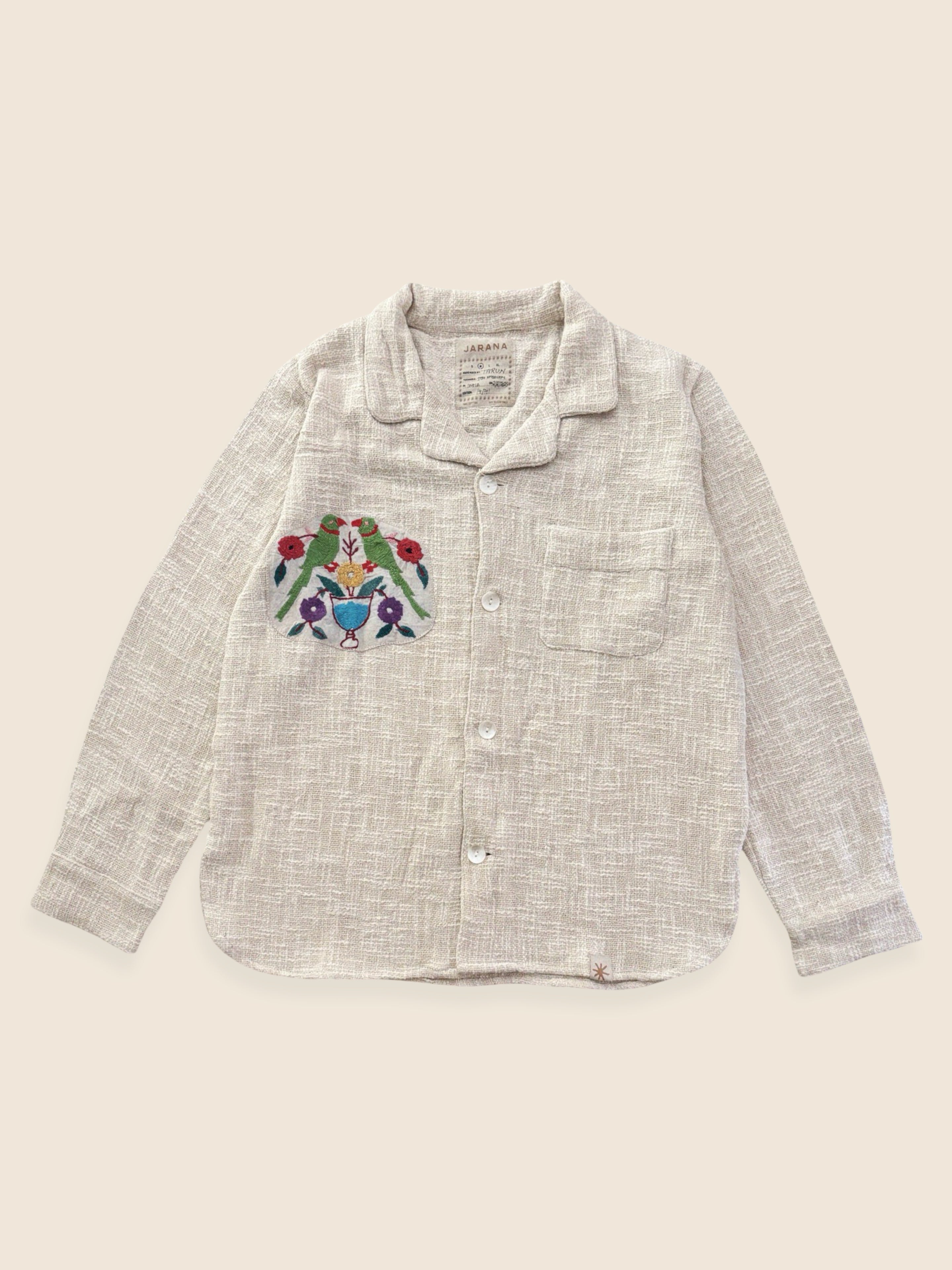 Embroidered shirt with a colorful design on a beige background