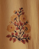 Detailed view of Jarana’s yellow cotton shirt showing a hand-block-printed floral bouquet in red and gold tones.