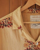 Shoulder and collar close-up of the Flor Baja block-printed shirt, showing intricate red leaf and flower pattern on soft yellow cotton.