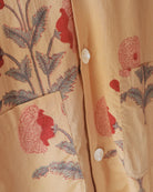 Close-up of lower pocket on yellow shirt showing detailed red floral block print and pearly button.