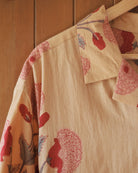 Shoulder and collar corner showing repeating red bud block print against light ochre fabric.