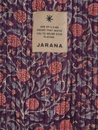 Close-up of purple quilted cotton covered in pink floral block print, accented by a Jarana badge.