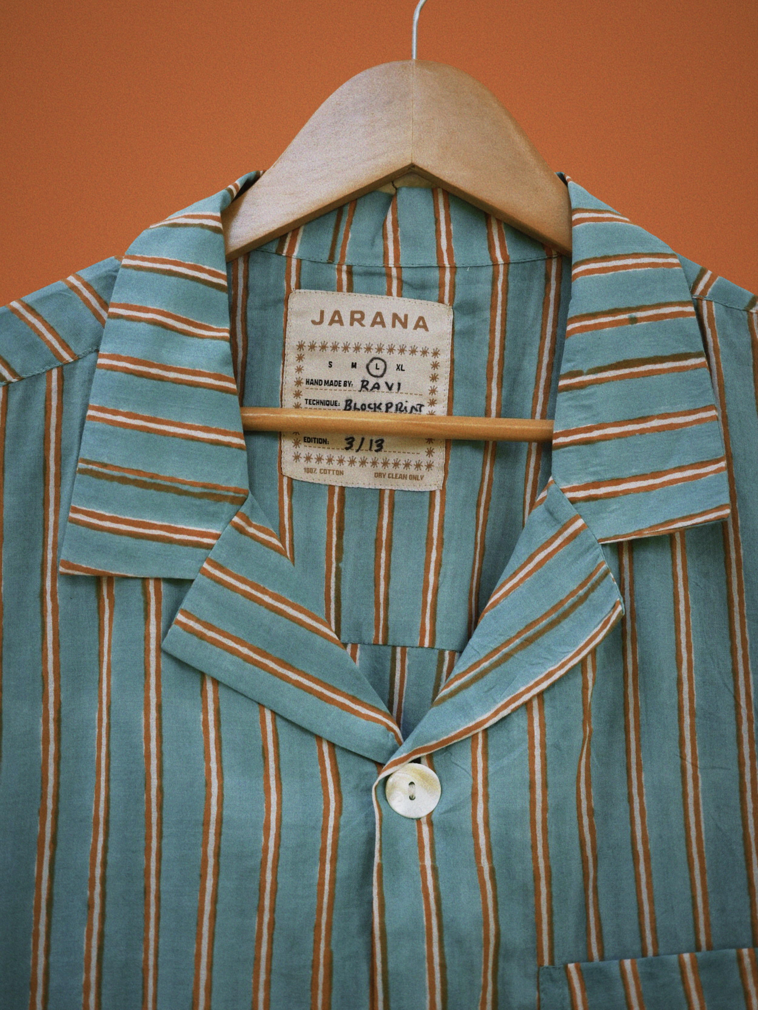 Collar and placket of teal cotton shirt with clay-brown vertical stripes and natural shell button.