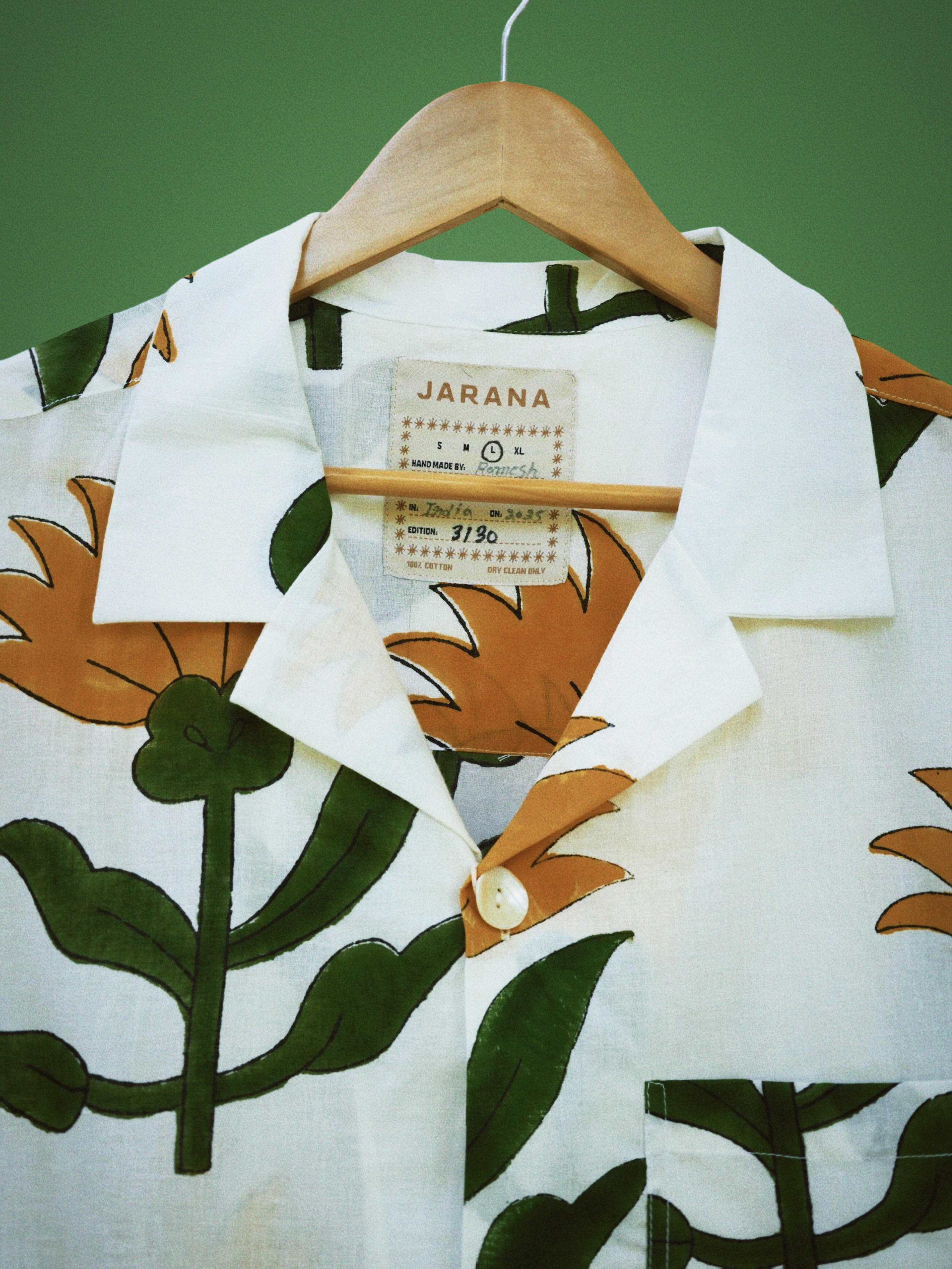 White cotton shirt featuring oversized sunflower and leafy green block print around the collar.