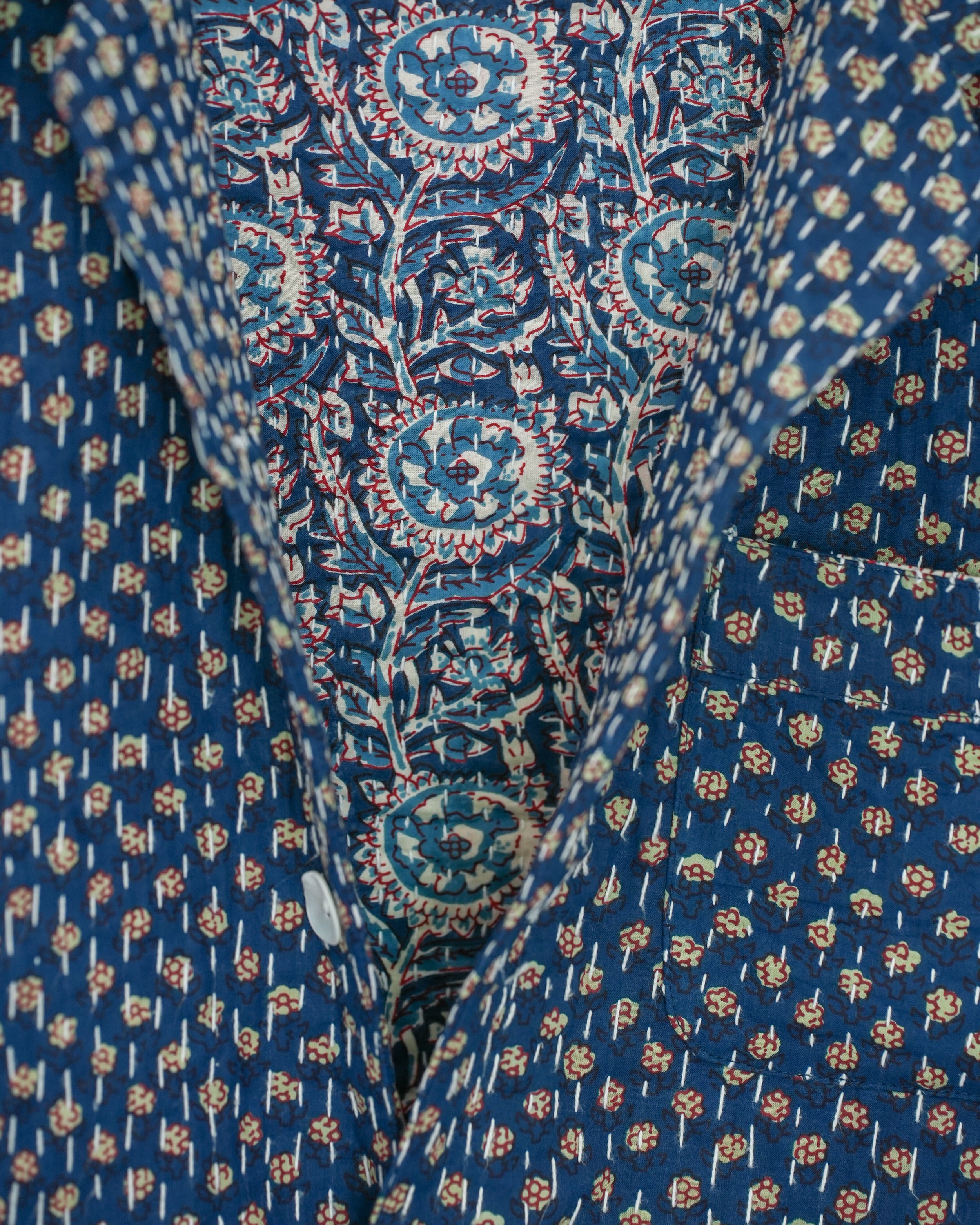 Close-up of blue fabric with fine Kantha embroidery and small traditional block-printed floral motifs
