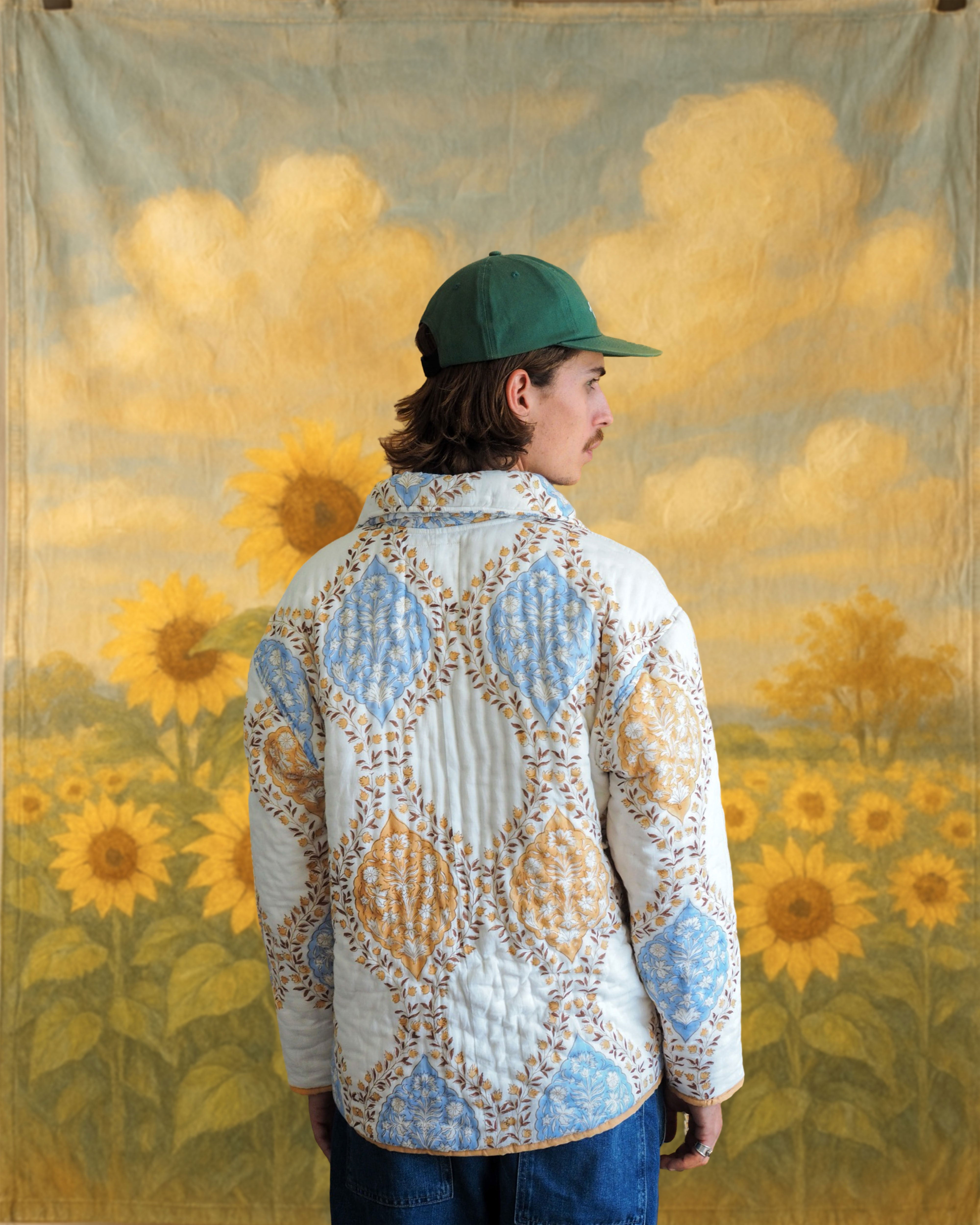 Model wearing quilted cotton jacket with hand blockprinted floral motifs in an outdoor sunflower backdrop