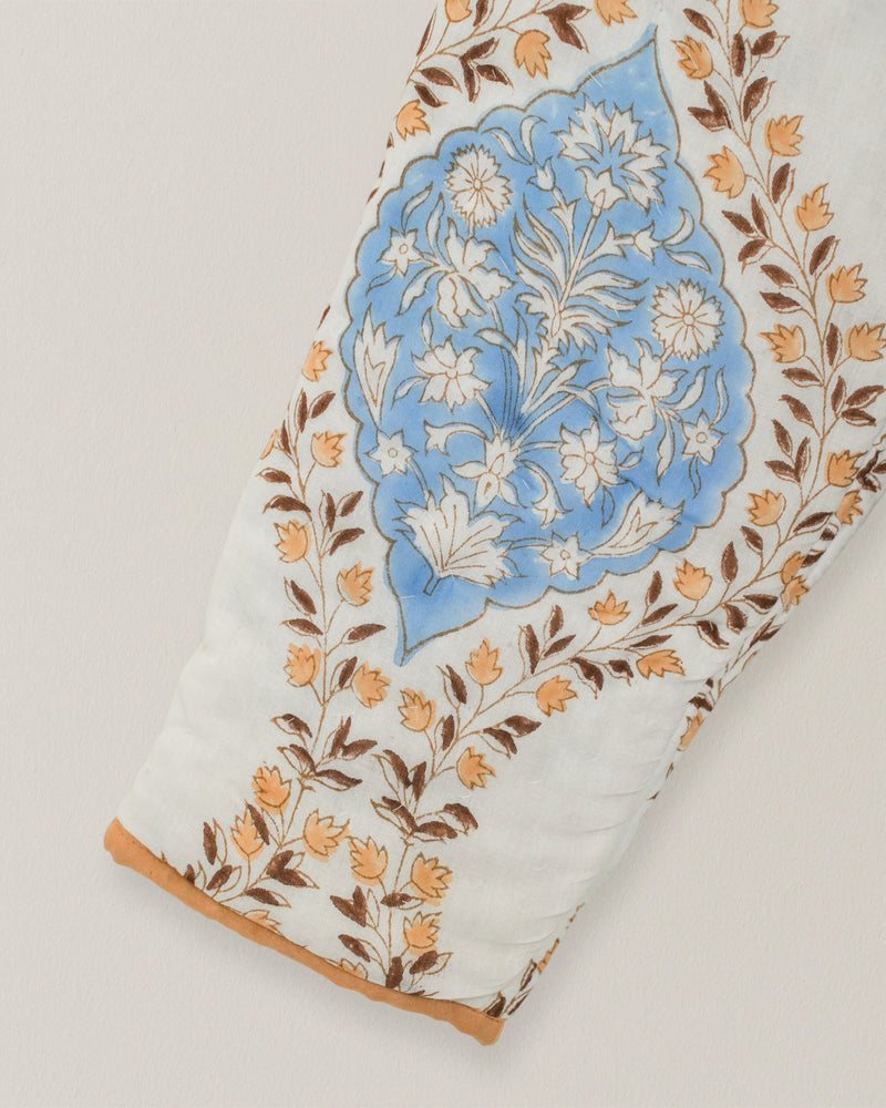 Close-up of quilted sleeve featuring blue floral blockprint motif with tan and brown leaf accents