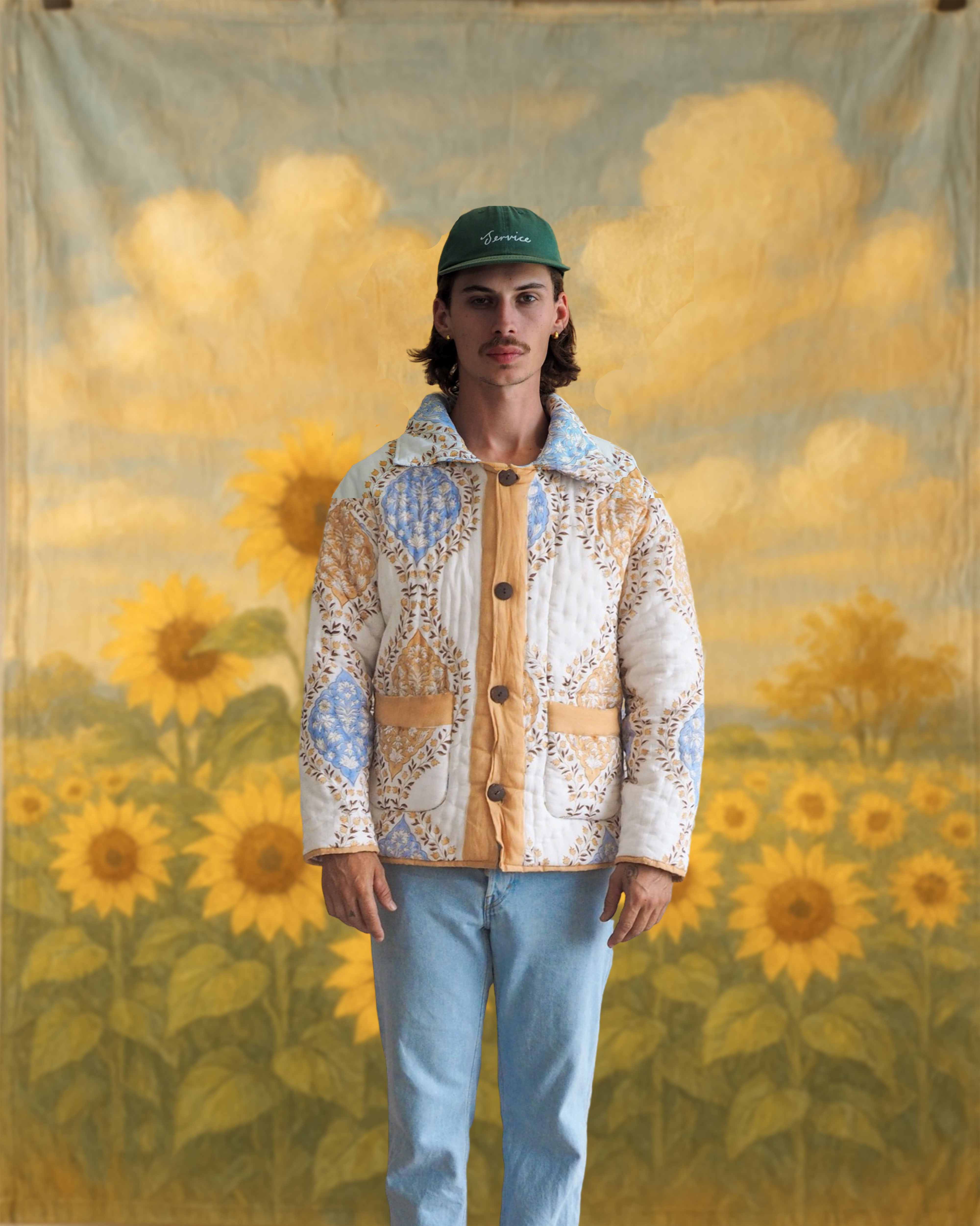Model standing front-facing in floral blockprinted quilted jacket and matching textile skirt with sunflower backdrop