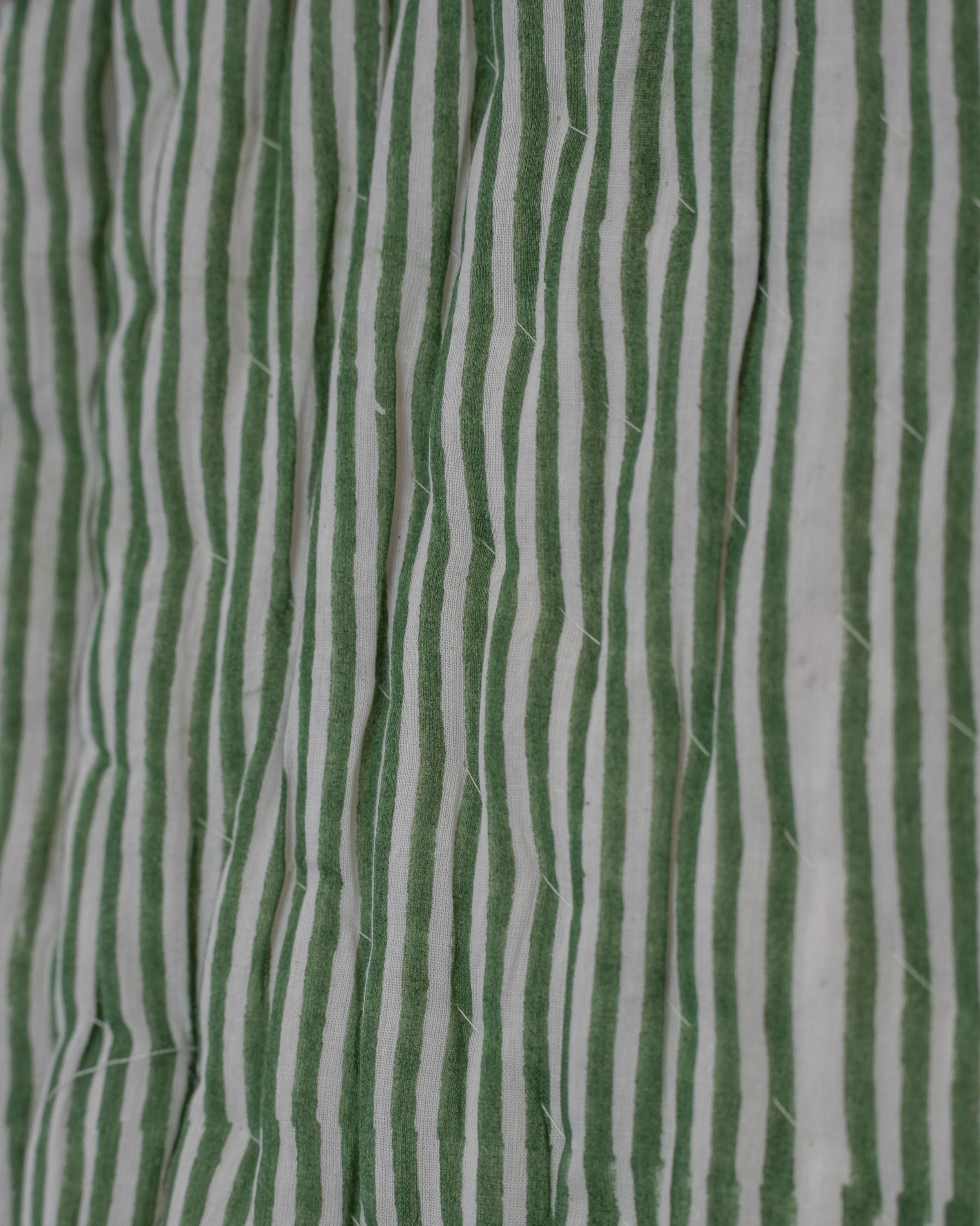 Macro detail of green and white striped blockprint fabric on quilted cotton jacket surface