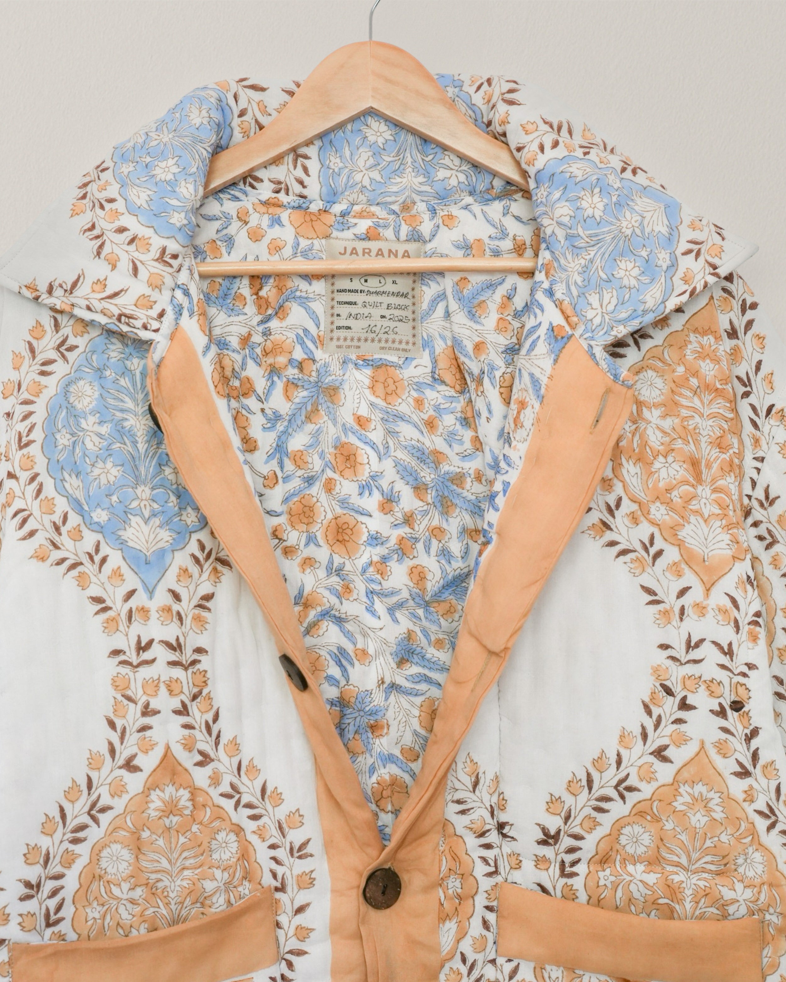 Interior of blockprinted quilted cotton jacket showing floral patterned lining and visible Jarana label