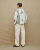 Person wearing a patterned sweater with floral designs on a beige background