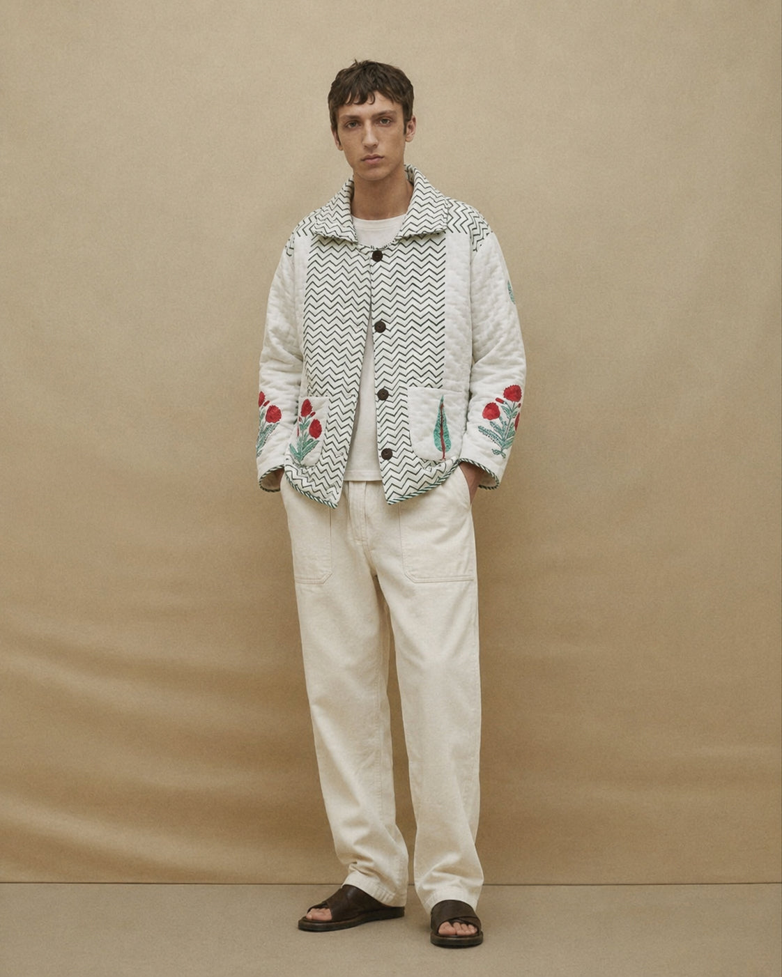 Person wearing a patterned jacket with floral designs on a beige background