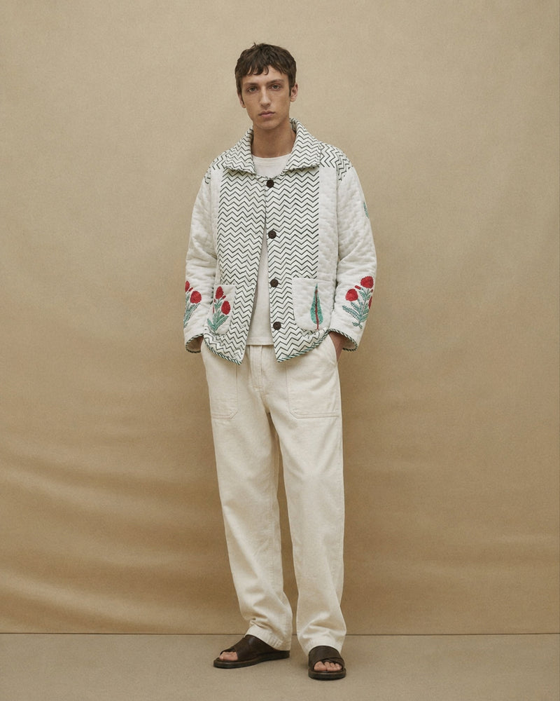 Person wearing a patterned jacket with floral designs on a beige background